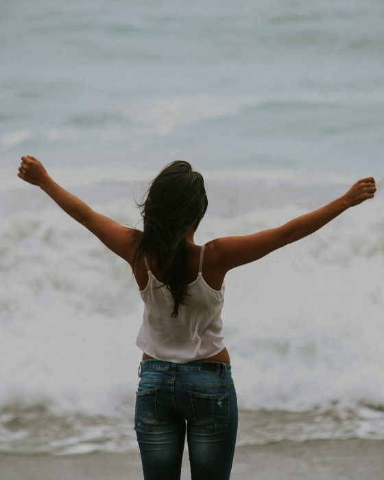woman in white spaghetti strap top standing on the seashore